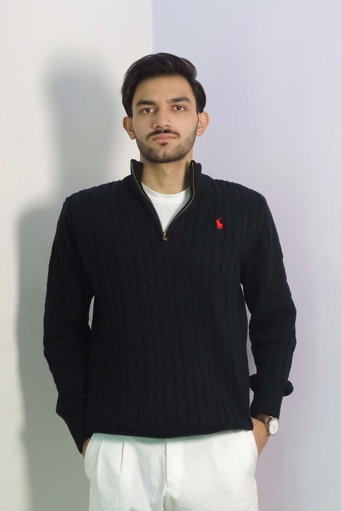 Man wearing a black sweater with a red logo on a light gray background