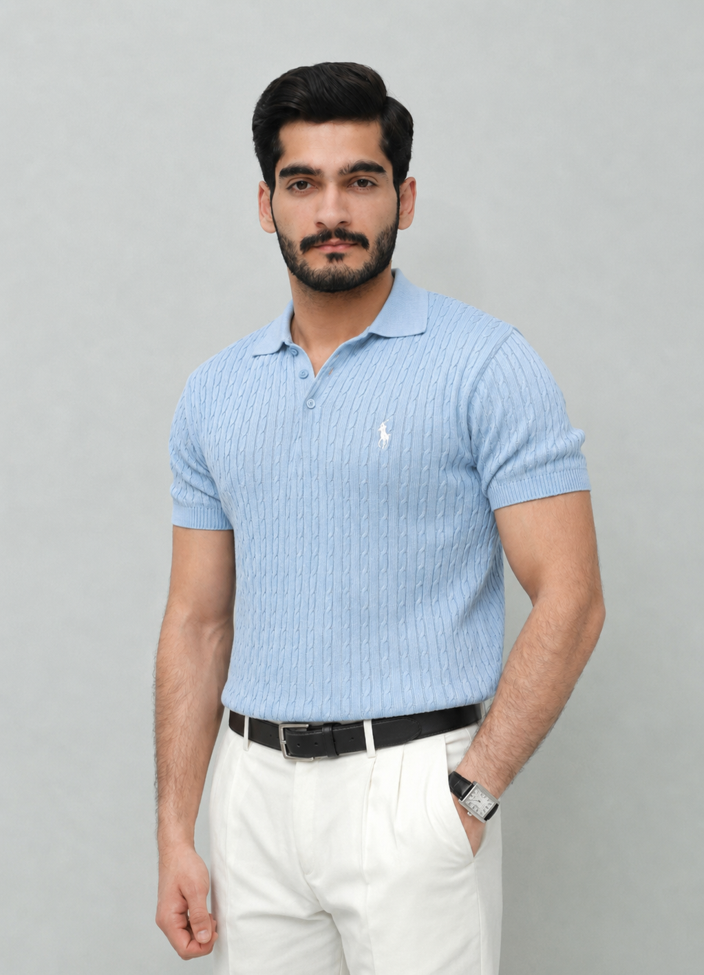 Man wearing a light blue polo shirt and white pants against a gray background