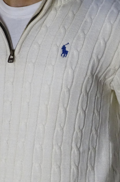 Close-up of a cable-knit sweater with a brand logo on a white background