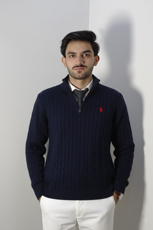 Man wearing a navy blue sweater with a red logo against a plain background