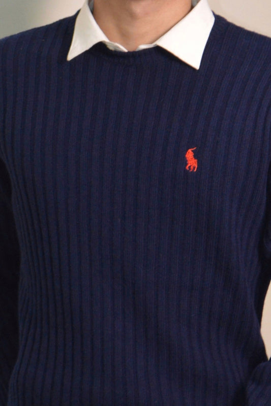 Navy sweater with a red logo worn by a person