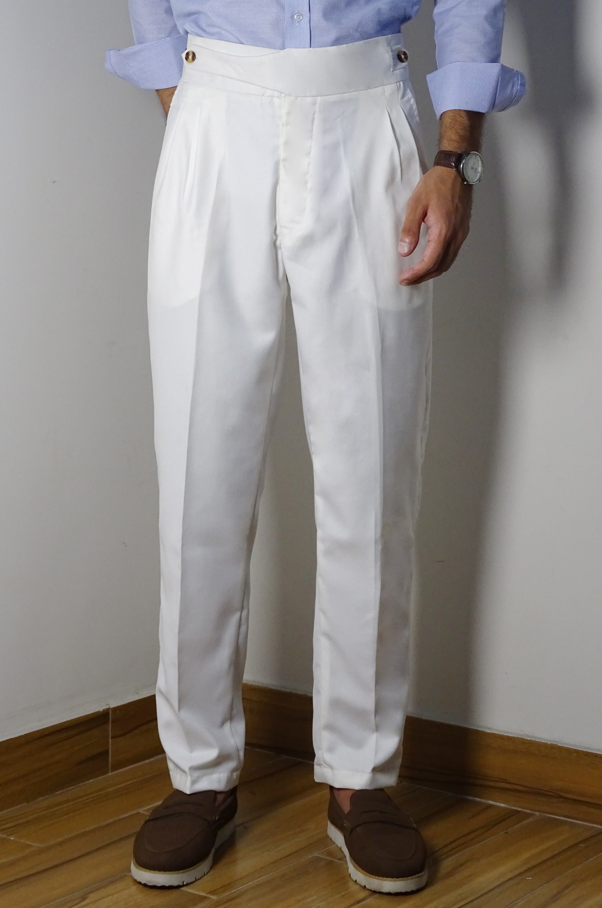 Person wearing white pleated pants with a plain background