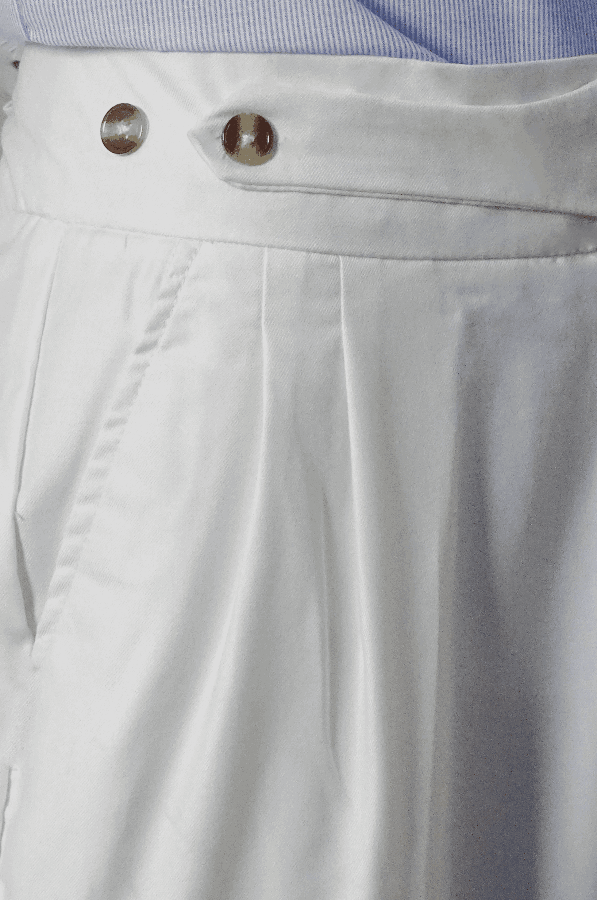 Close-up of light gray pants with a button and zipper detail.