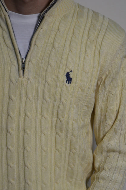 Light yellow cable knit sweater with a brand logo on a plain background